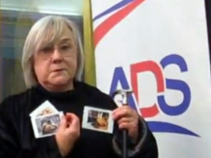 An activist holds photos of victims of conflict beside an ADS sign.