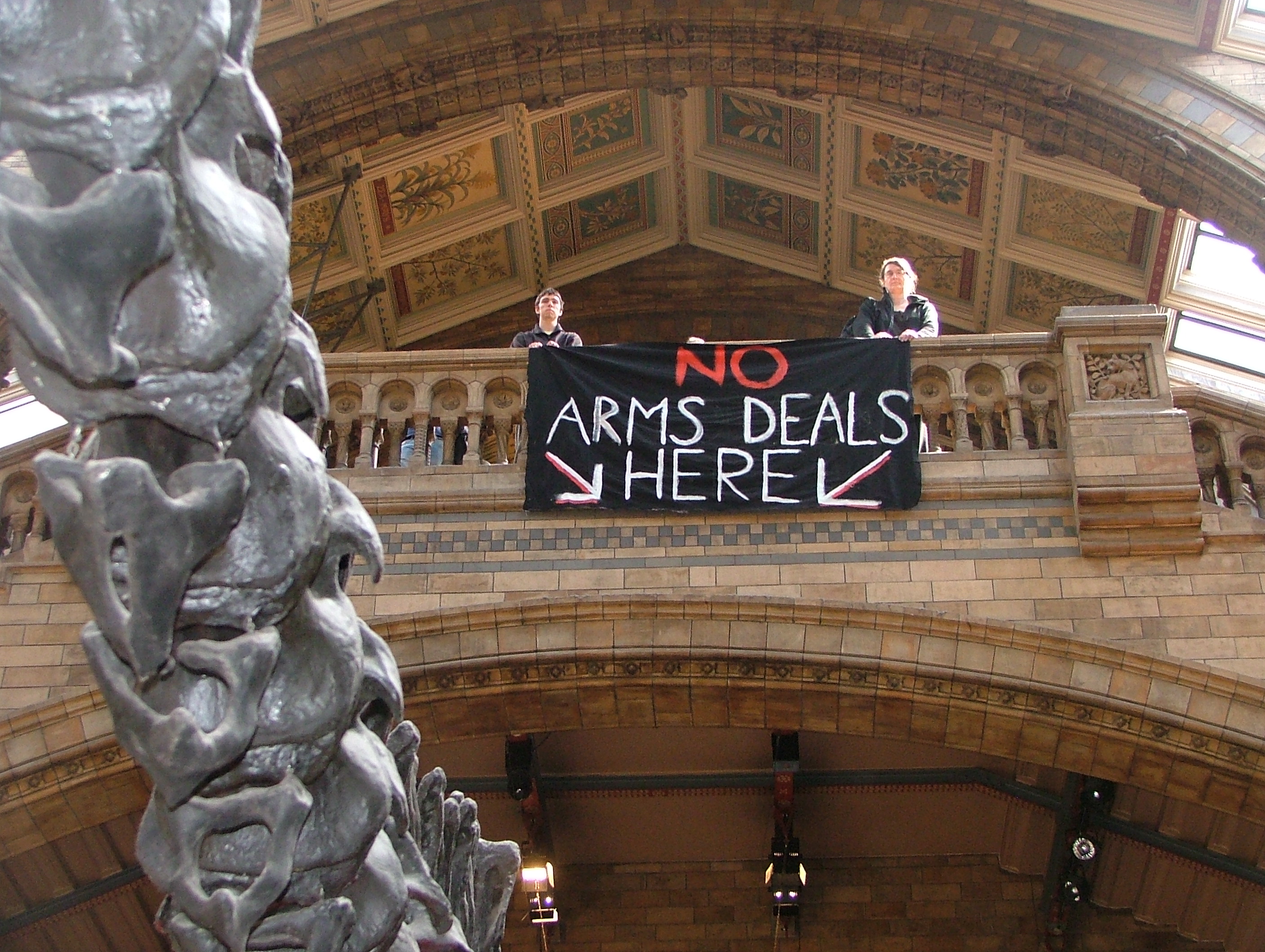 Banner drop above the dinosaur at the Natural History Museum - 'no arms deals here'
