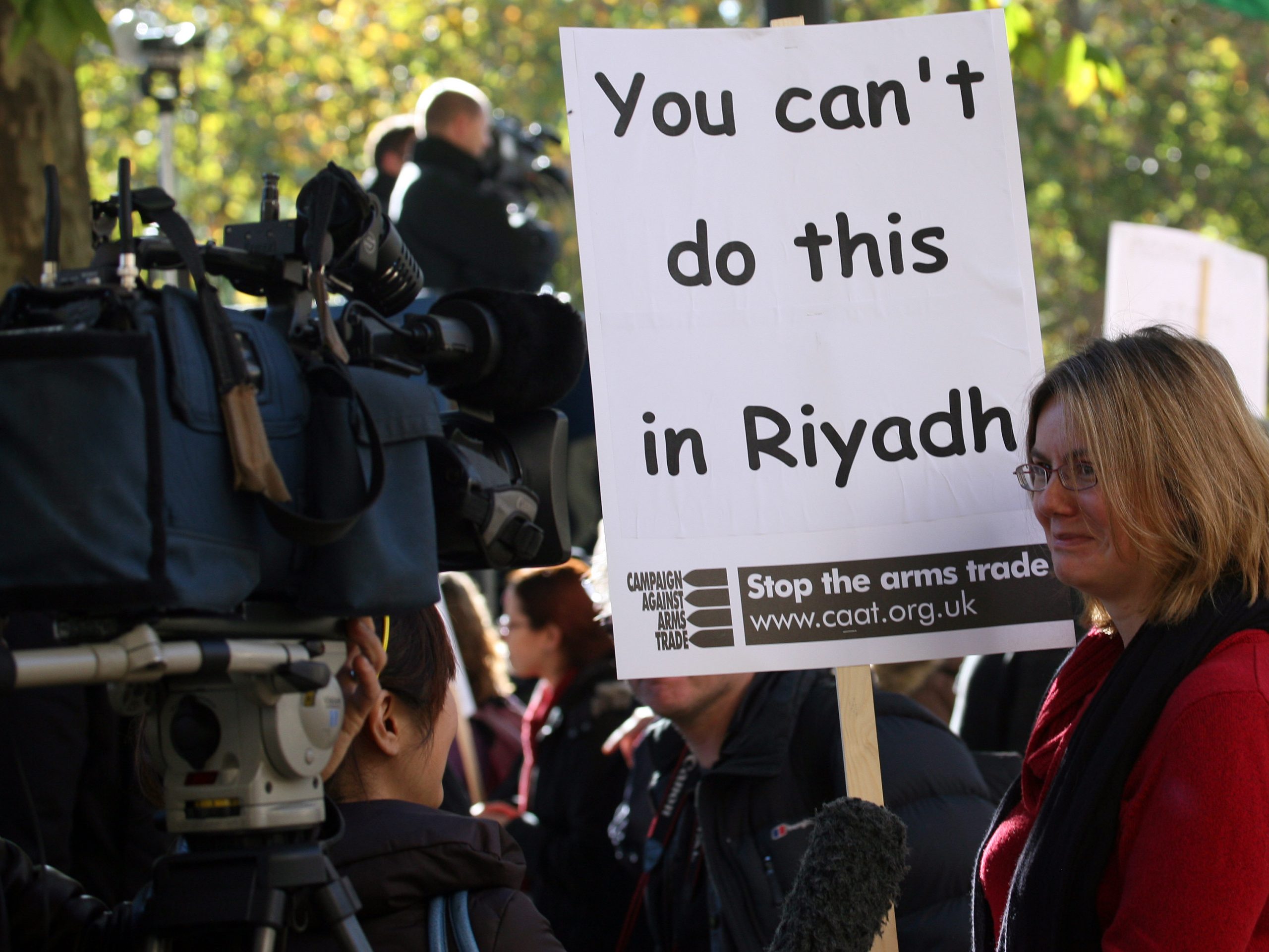 A protester holds a CAAT placard saying &quot;You can't do this in Riyadh&quot;.