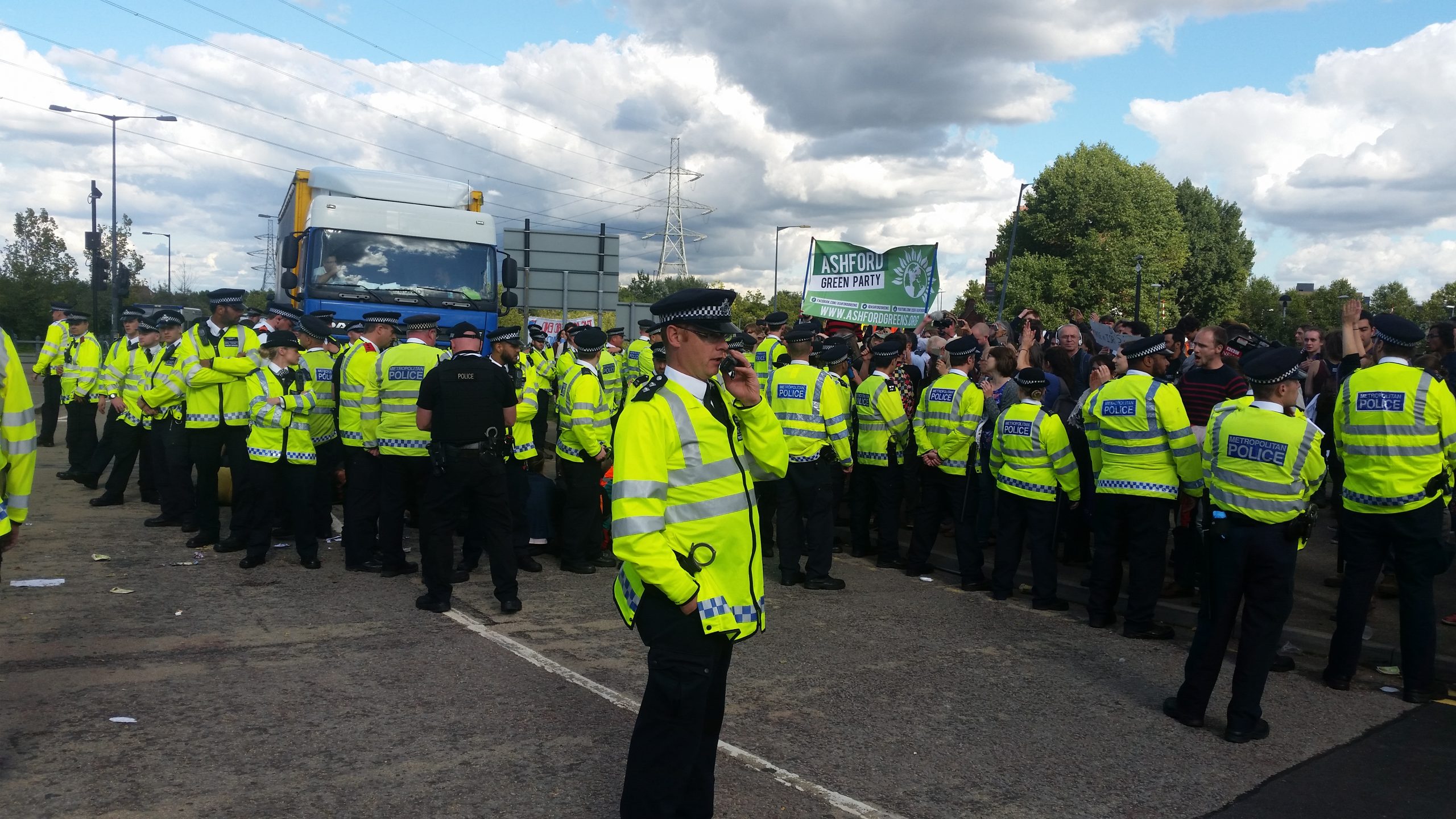 A line of police stand in front of an HGV lorry