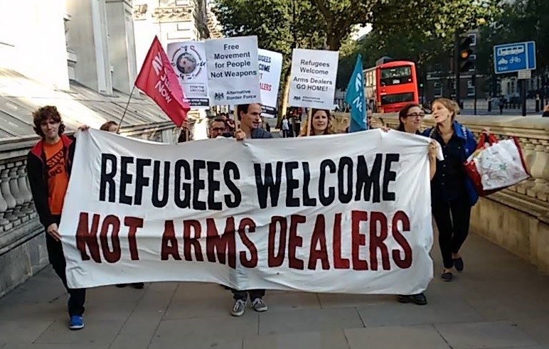 A group of activists hold a 'Refugees Welcome, Not Arms Dealers' banner