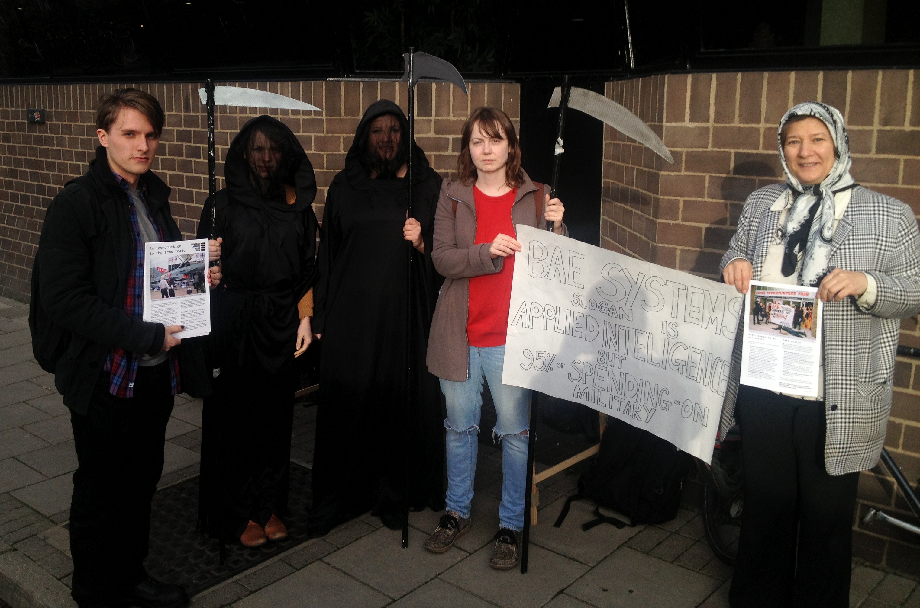 Students dressed as grim reapers hold banners and signs.