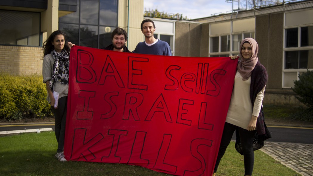 Four students hold a banner that says "BAE sells Israel kills".