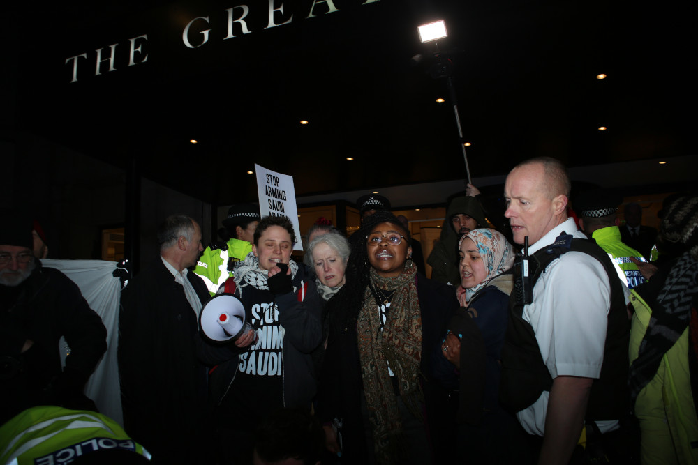 Protesters with a megaphone and Stop Arming Saudi palacrd outside the arms dealers&#039; dinner