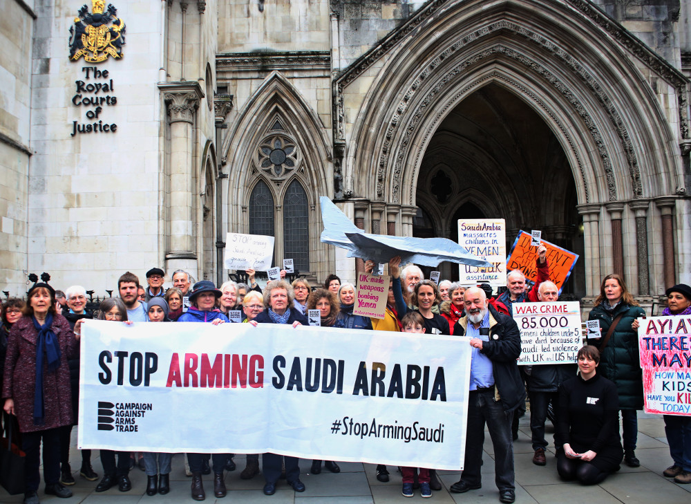 People gathered outside the entrance to the Royal Courts of Justice,behind a banner saying &quot;Stop Aarmign Saudi Arabia, other hand-painted placards, and a model Eurofighter Typhoon, saying UK made weapons bombing Yemen.