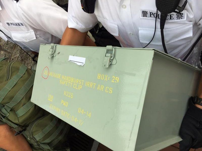Hong Kong police office holding metal box with marking indicates it contains UK-made teargas