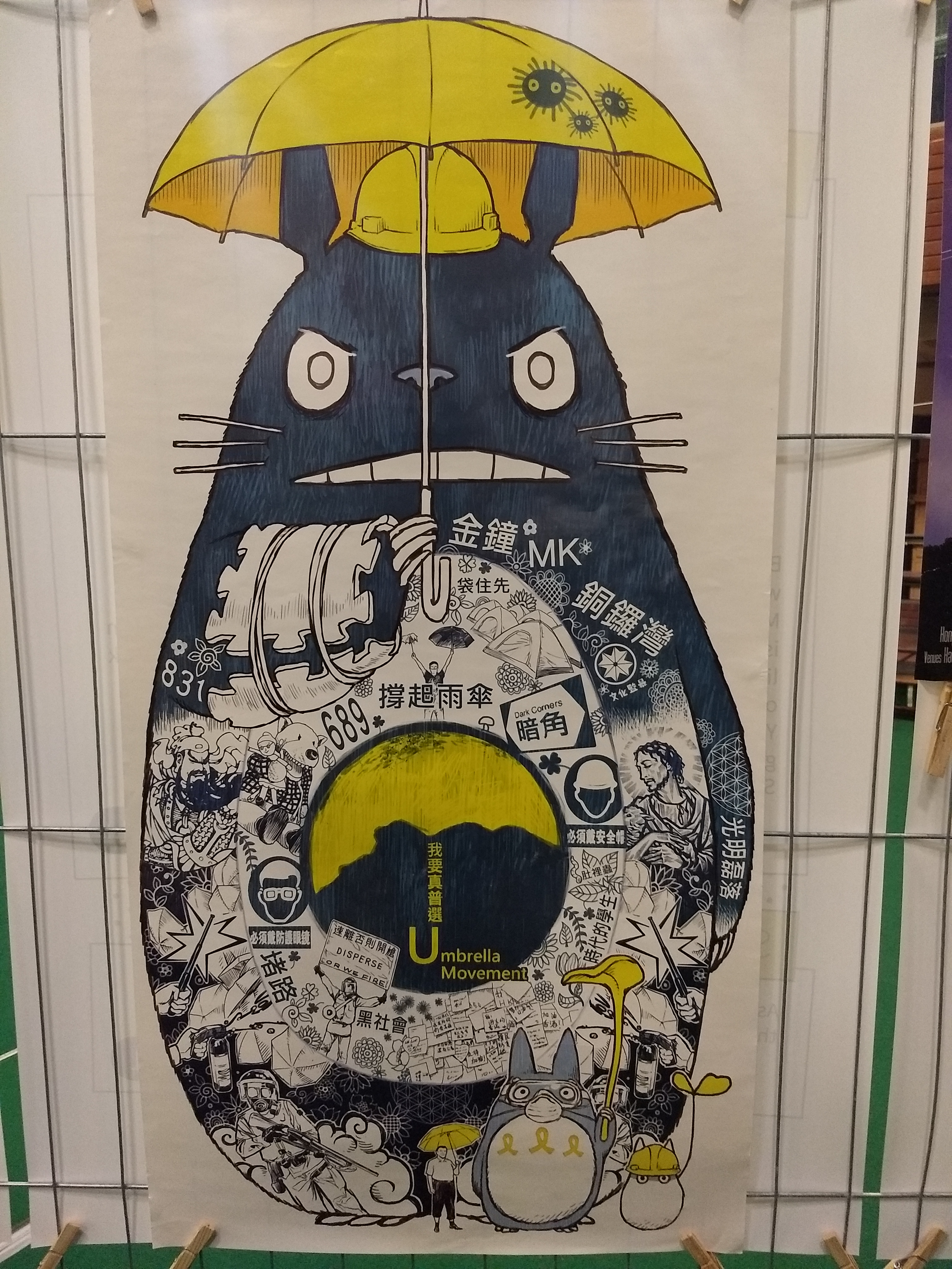 A drawing of an animal wearing a yellow hard hat and holding a yellow umbrella. The body of the animal is covered in protest drawings.