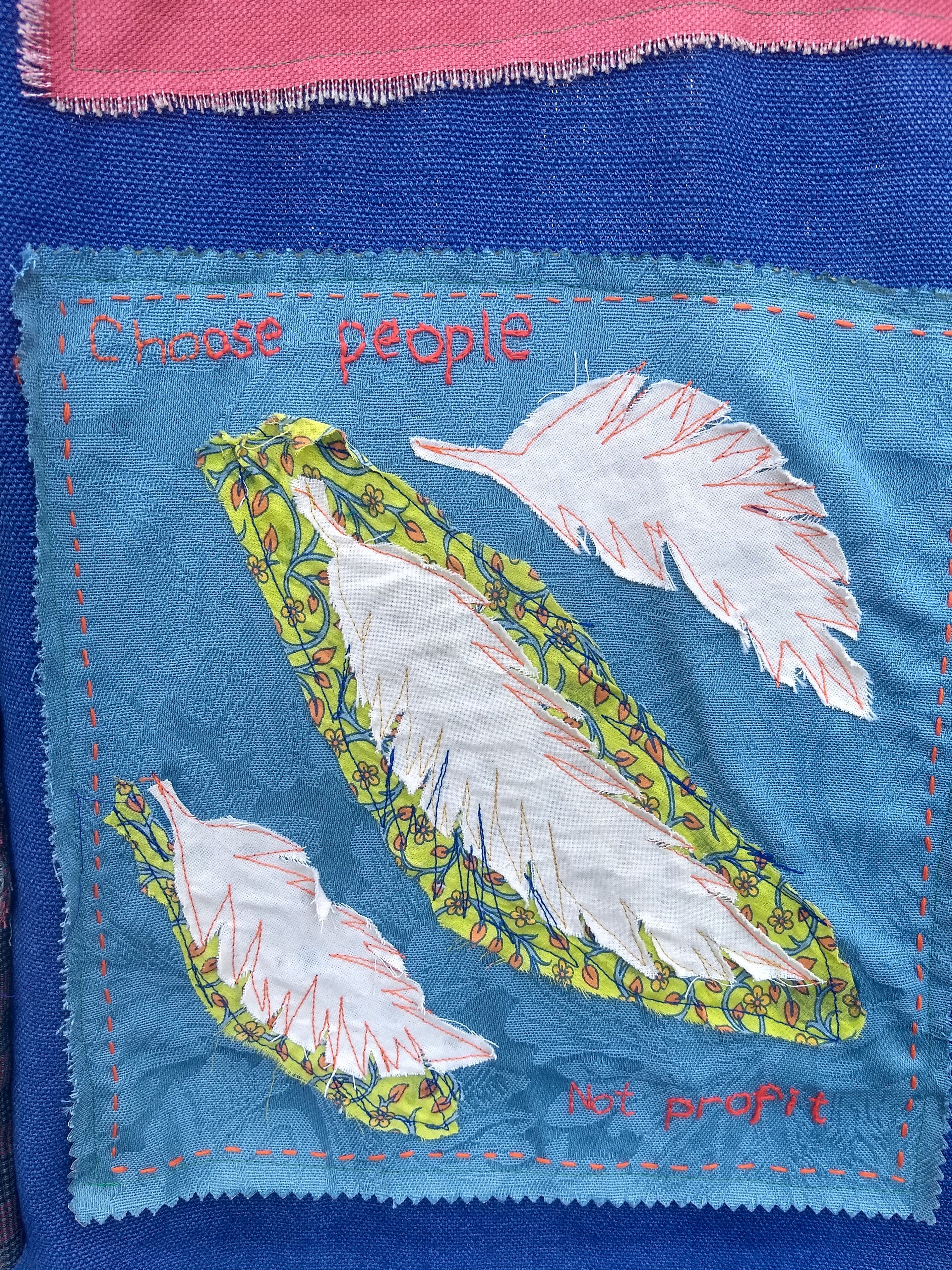 A small hand sewn banner reads 'Choose people', hung at the DSEI arms fair week of action, 2019