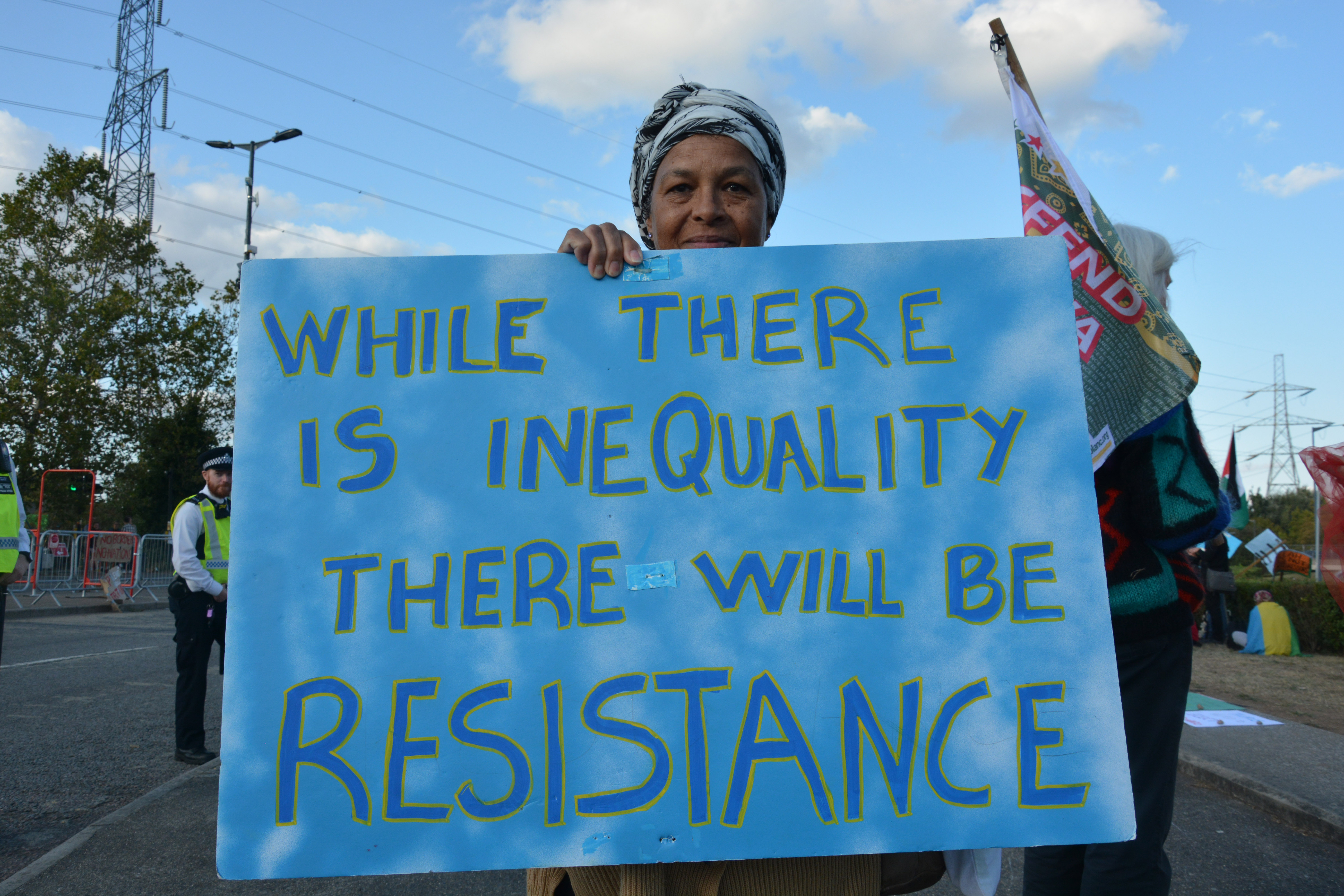 Activist with banner that says while there is inequality there will be resistance