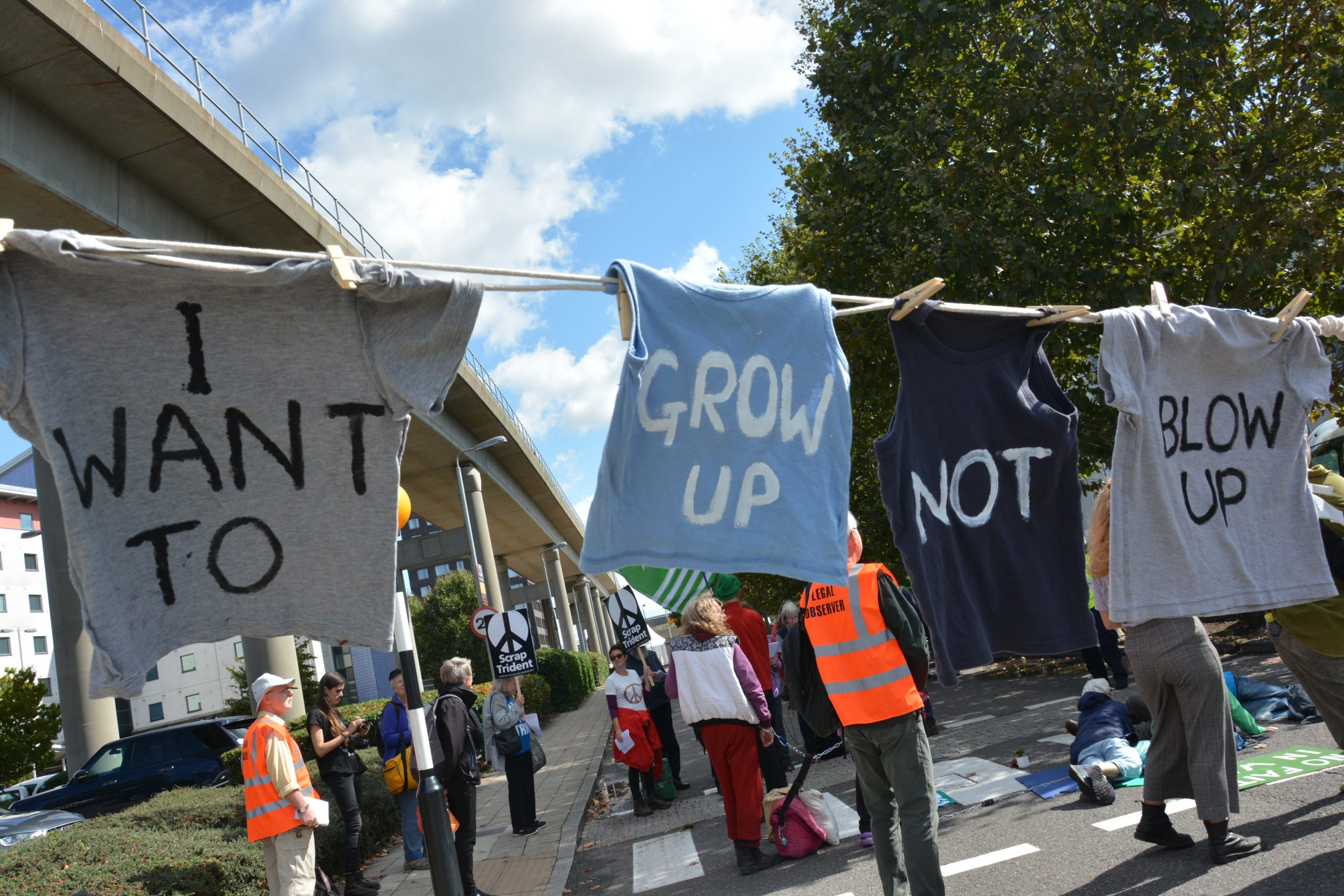 Children's clothes hanging outside DSEI that read 'I want to grow up not blow up'