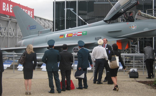 People looking at a combat aircraft at an arms fair