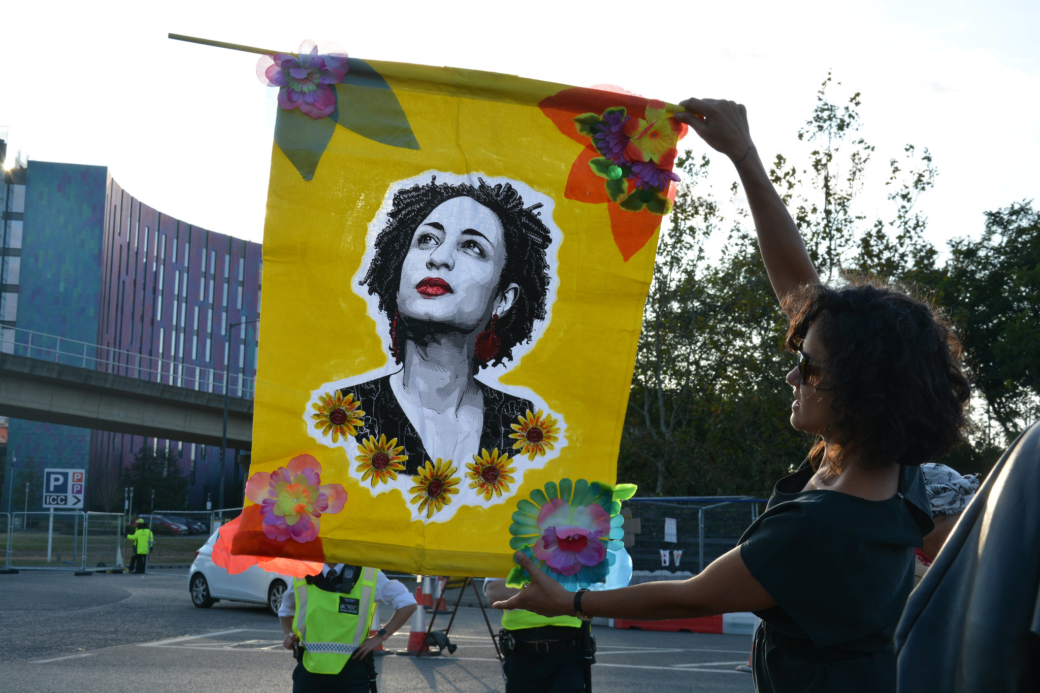 Activist holding up image of a person wearing red lipstick and sunflowers on a yellow background