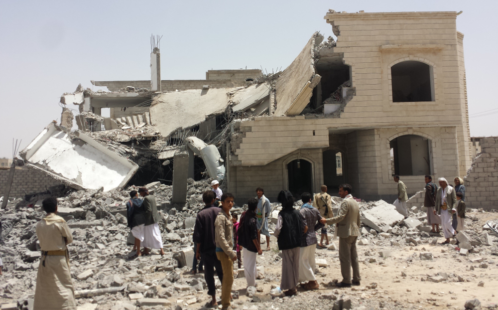 A destroyed house in Sanaa with crowd of rescuers in front