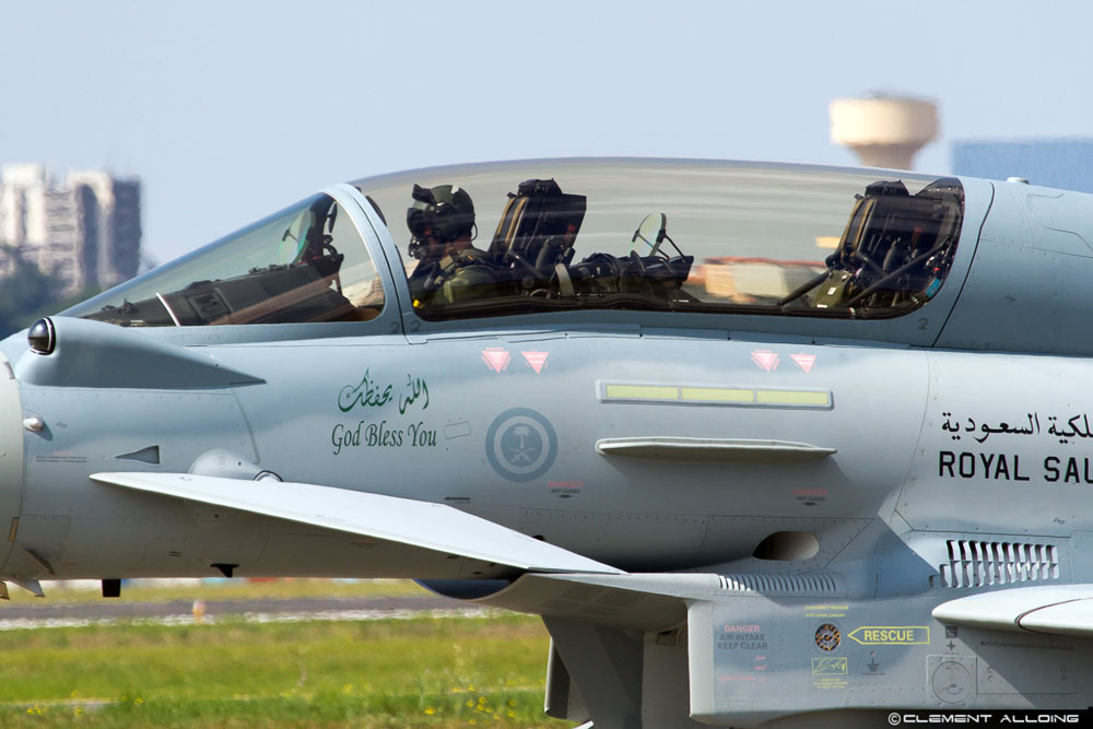 Royal Saudi fighter jet, picture of pilot under canopy. Decals on jet say God Bless You and Royal Sau in Arabic and English