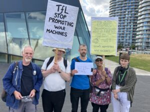 A group of protesters hold signs outside City Hall saying TfL Stop Promoting War Machines and BAE Systems off the rails
