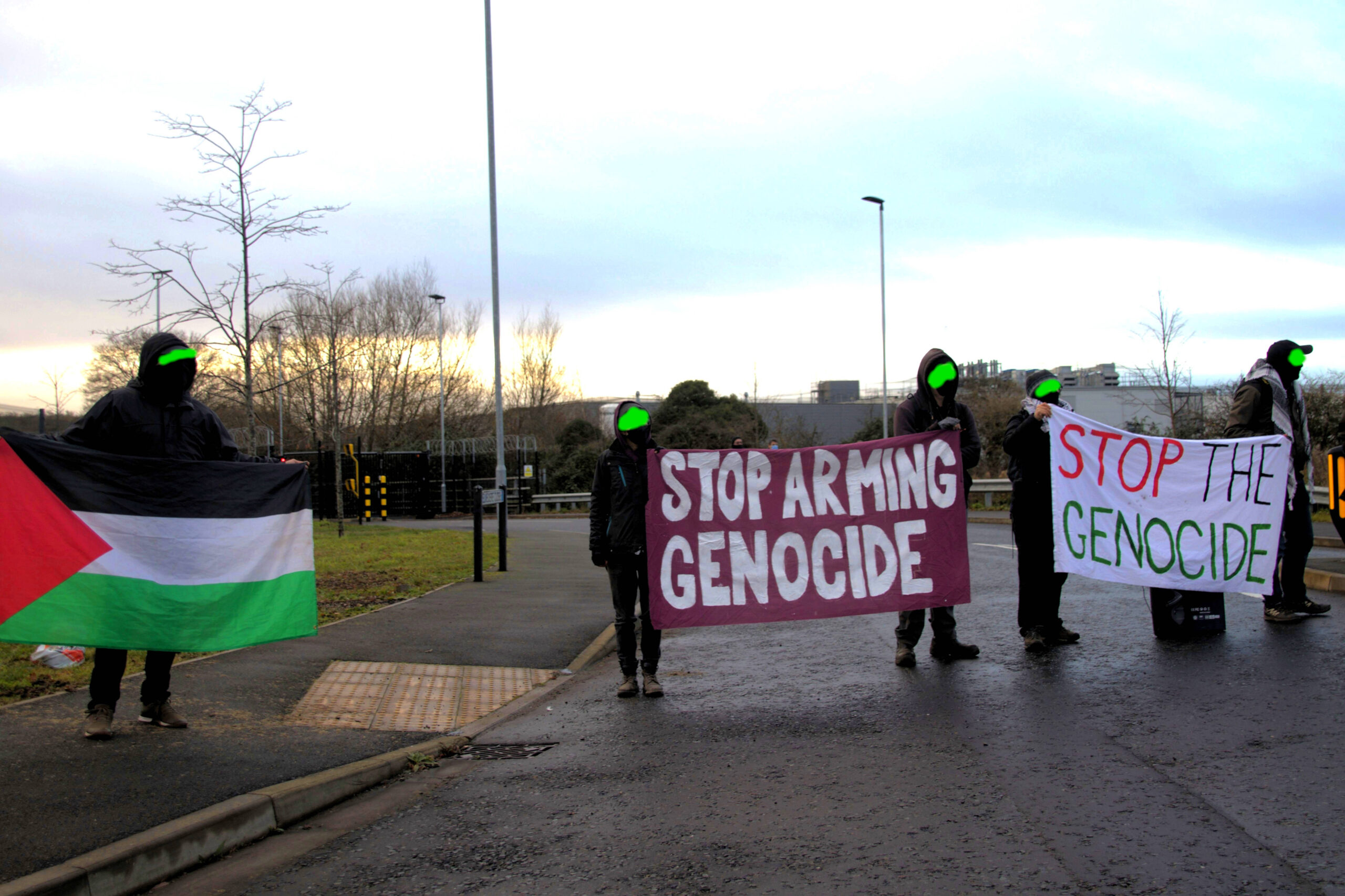 Local residents outside Elbit in Bristol with a Palestinian flag and a banner reading stop genoicde