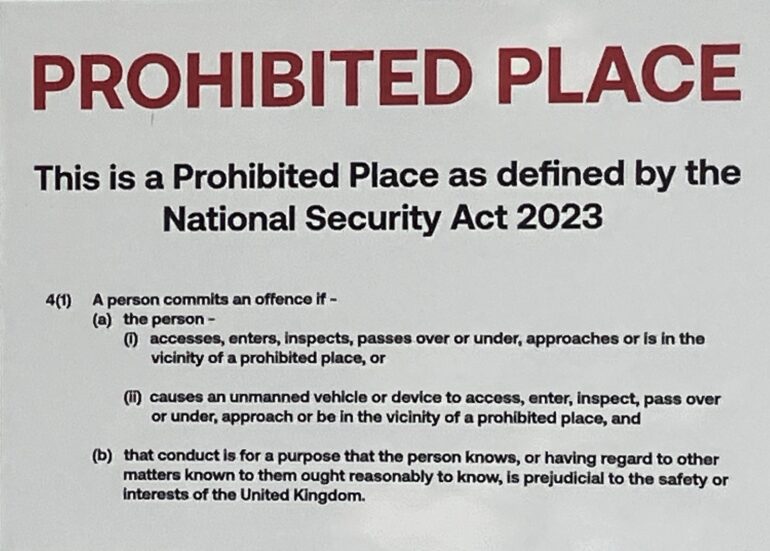 Image is of sign outside Elbit Systems in Bristol that reads Prohibited Place. This is a Prohibited Place as defined by the National Security Act 2023 and then has details of the legislation.