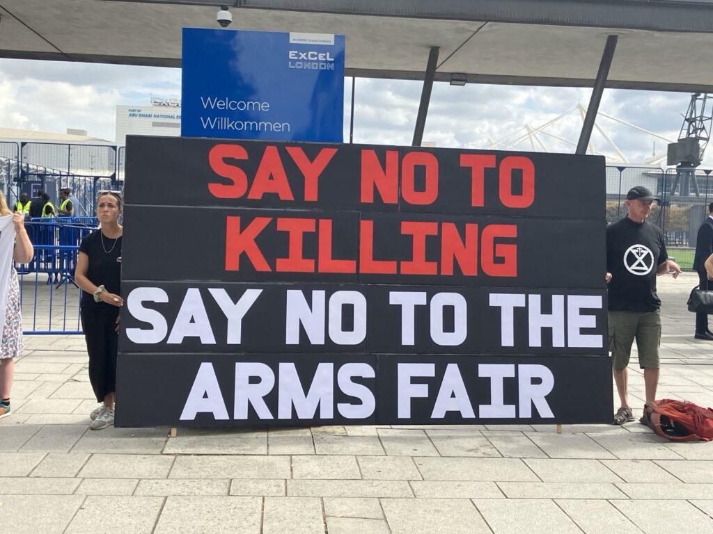 Banner outside the ExCeL centre reading Say not to Killing. Say no to the arms fair