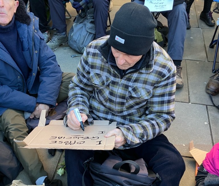 A person on a defend our Juries protest starts to wtite a placard