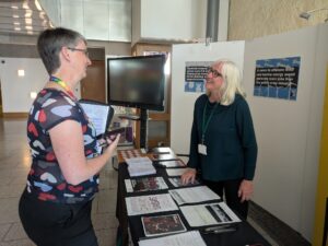 Maggie Chapman MSP talks to a volunteer at the CAAT stall in the Scottish Parliament.
